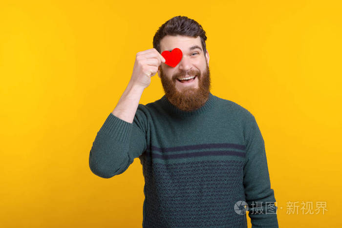 兴高采烈的年轻人拿着红纸心捂着眼睛