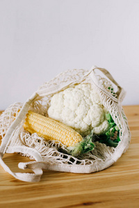 新鲜的玉米和花椰菜放在木桌上的环保袋里拯救地球