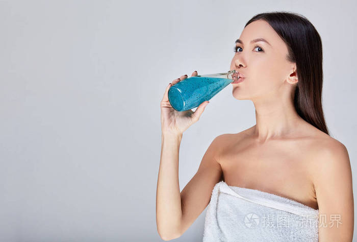 性感的亚洲女人在水疗后喝排毒鸡尾酒。