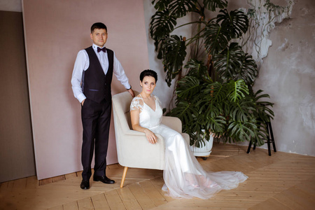 Beautiful bride in an elegant dress sitting in a pink chair and 