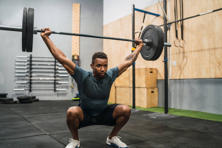 Crossfit athlete doing exercise with a barbell. 