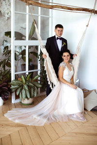 美丽的新娘穿着优雅的礼服坐在一个macrame吊床上