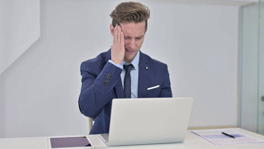 Tired Young Businessman having Headache in Office 