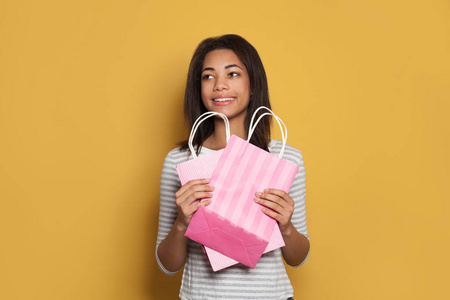Pretty young African American woman holding pink shopping bags 