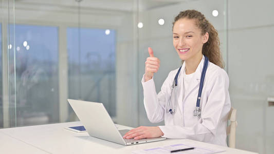 Beautiful Young Female Doctor Working on Laptop and Smiling 