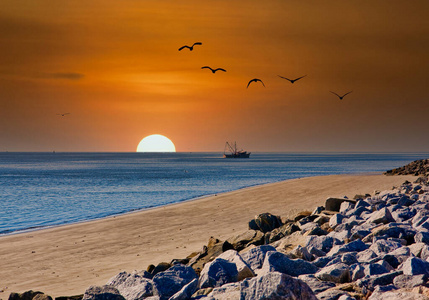日落时，捕虾船经过岩石海滩