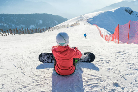 滑雪女孩和滑板坐在山上的滑雪坡上
