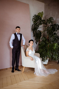 Beautiful bride in an elegant dress sitting in a pink chair and 