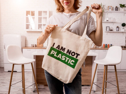 Young girl holding a cloth bag. At the kitchen. I am not plastic