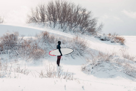 Cold winter and surfer with surfboard. Snowy day with surfer in 