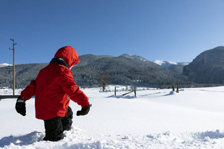 一个男孩在冬天走过厚厚的易碎的雪。