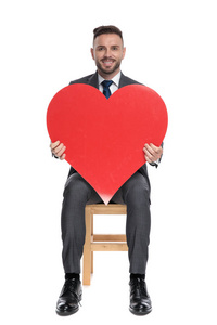 happy young businessman holding big red heart 
