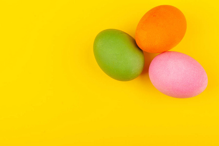 彩色手工复活节彩蛋。三个鸡蛋的俯视图。被隔离在黄色背景上。准备复活节。