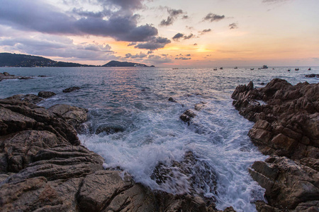 石头海岸，泡沫波浪和美丽的日落。泰国