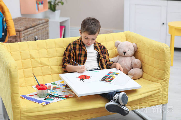 小孩子在家里的沙发上画画