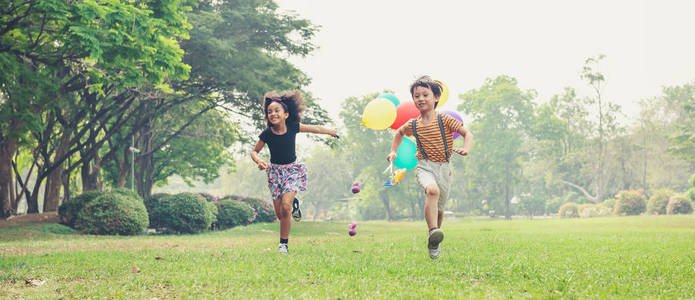 two kids running in the spring field at public park 