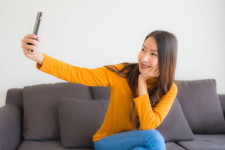 年轻的亚洲女性在沙发上使用智能手机