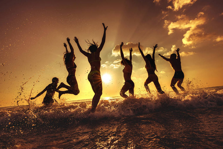 一群快乐的朋友在日落海滩玩