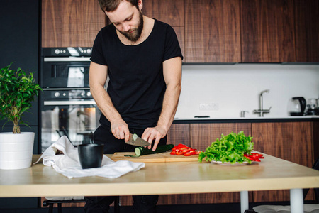 一个男人正在厨房的菜板上切蔬菜