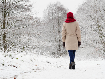 女人在冬天的雪林里散步。