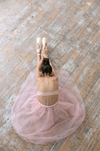 vertical photo of a young ballerina sitting on the floor in the 