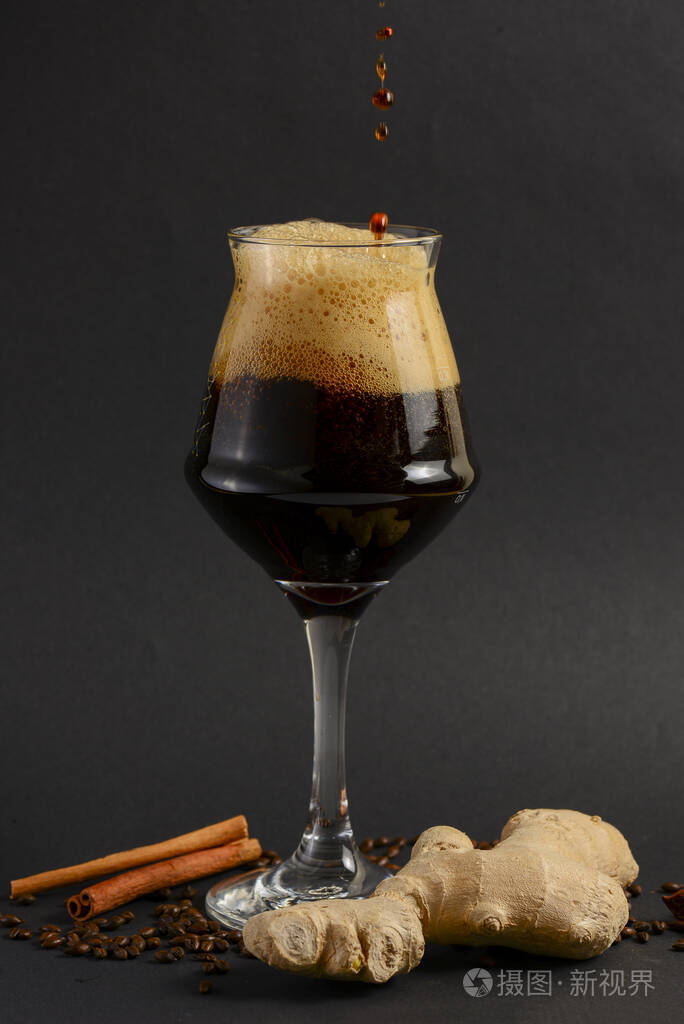 一大杯黑色背景上有香料的黑啤酒啤酒花茴香肉桂姜复制空间