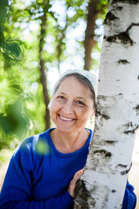  Beautiful elderly woman in   white scarf against  nature.