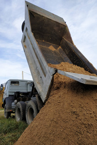 一辆自卸车在建筑工地卸沙子拌水泥.照片