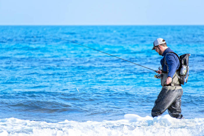 站在海边的渔夫抛下鱼竿运动员拿着鱼竿卷起一条带钩的鱼旋转钓鱼爱好