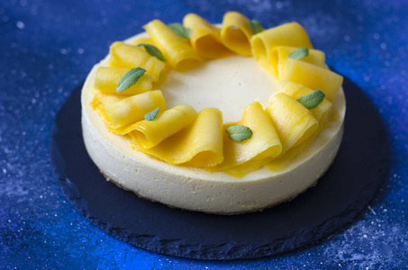 Cheesecake with mango and mint on a blue board  