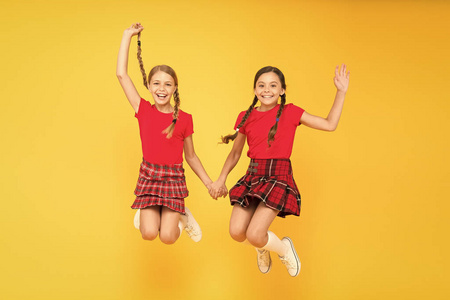 加入庆祝活动。小女孩穿格子连衣裙。国庆节。校服。苏格兰风格。快乐的朋友女生们跳着黄色的背景。庆祝节日。苏格兰假日