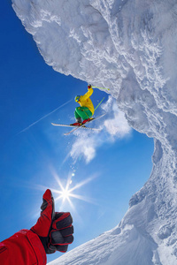 滑雪者从岩石上跳着蓝天