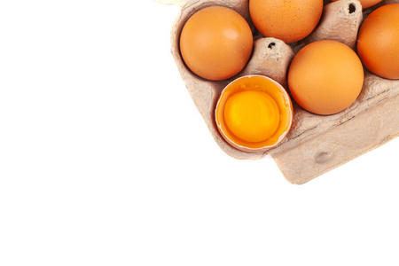 鸡蛋鸡蛋。打开的灰色盒子的俯视图，白色背景上隔离了棕色的鸡蛋。一个鸡蛋半碎，黄而圆的蛋黄。健康的生活方式，获取纯蛋白质
