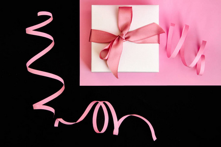 粉红色和黑色背景上有粉色丝带的礼品盒