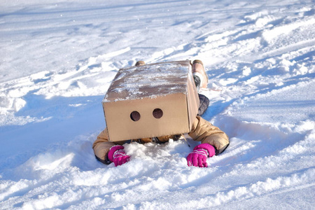 那女孩在箱子下面爬。让孩子们兴奋的寒假。学校外的冬季活动。雪上游戏