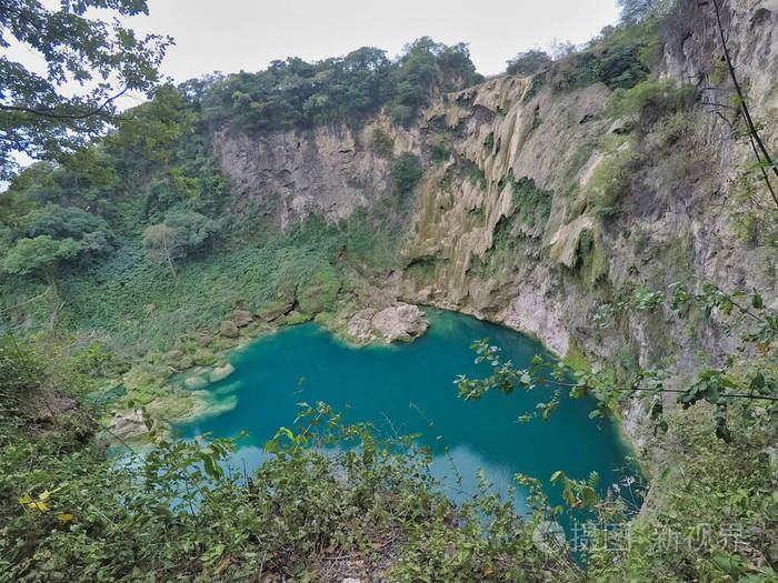 在墨西哥圣路易斯波托西EL SALTOEL MECO的瀑布，一名妇女站在岩石上，伸出双手欣赏瀑布