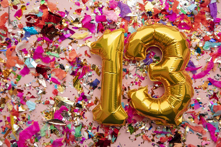 13号金色生日庆祝气球，背景是五彩纸屑