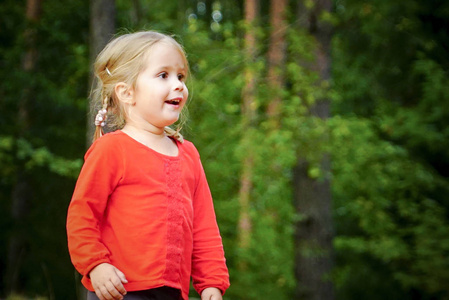 一个3岁的小女孩在森林里的空地上玩耍。