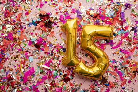 15号金色生日庆祝气球，背景是五彩纸屑
