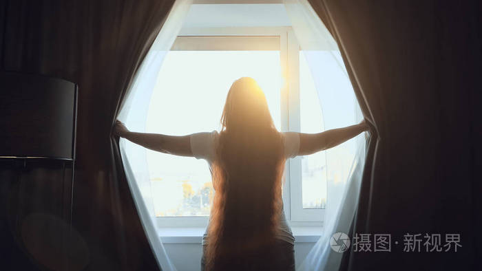 女人在家里打开窗帘迎接早晨的阳光