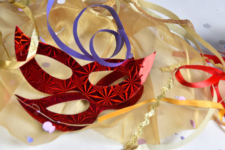 red carnival costume mask in colorful confetti and streamers on 