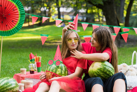 两个漂亮的少女在公园里吃西瓜玩得很开心.天气晴朗.夏季概念.
