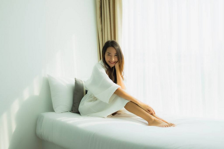 年轻的亚洲女人快乐的微笑在卧室的床上放松