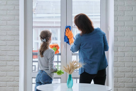 母女俩带着手套用抹布一起擦窗户
