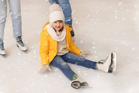 可爱的小女孩在溜冰场上摔倒了照片