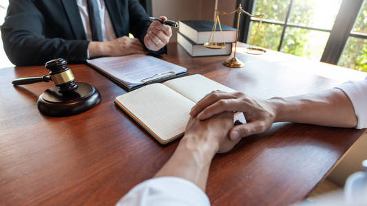 男性公证律师或法官在办公室法律和法律服务理念下与客户咨询或讨论合同文件。