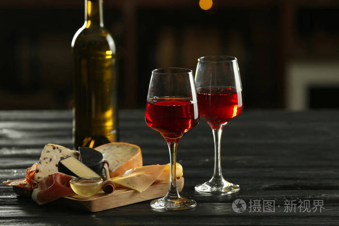 酒杯和一瓶可口的葡萄酒在酒吧的桌上摆着小吃