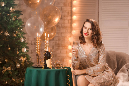 一位年轻漂亮的女士在为圣诞节装饰的房间里喝着香槟