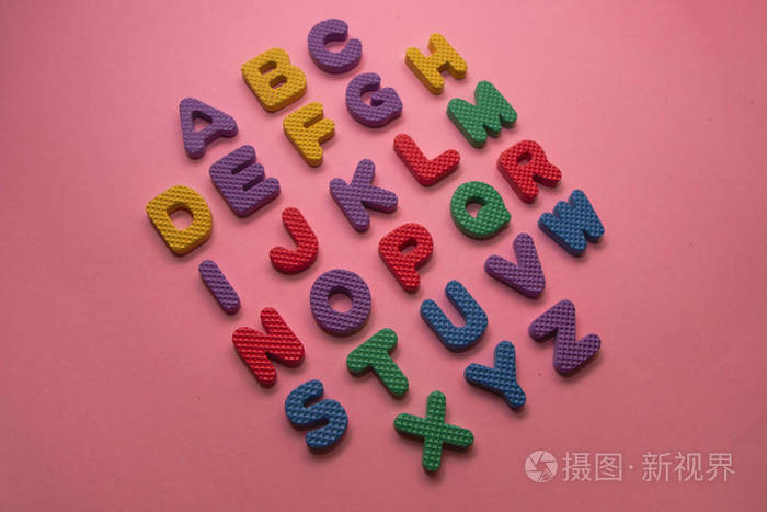 粉红色背景的彩色塑料英文字母