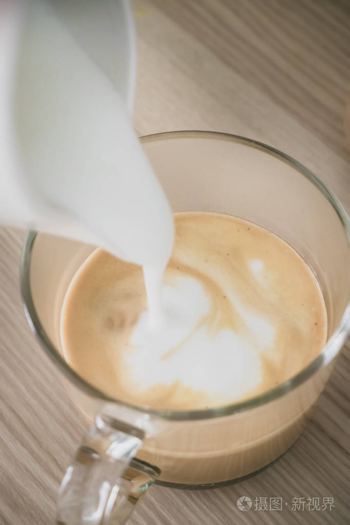 牛奶泡沫正往咖啡里倒